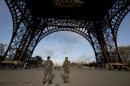 French soldiers patrol at the Eiffel Tower which remained closed on the first of three days of national mourning in Paris, Sunday, Nov. 15, 2015. Thousands of French troops deployed around Paris on Sunday and tourist sites stood shuttered in one of the most visited cities on Earth while investigators questioned the relatives of a suspected suicide bomber involved in the country's deadliest violence since World War II. (AP Photo/Peter Dejong)