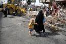 A woman walks with her child through the aftermath of a car bomb attack in the crowded commercial area of Karrada, in Baghdad, Iraq, Friday, April 18, 2014. Authorities in Iraq say a car bomb targeted a street full of shoppers in the capital. in Baghdad on Thursday,AP Photo/Karim Kadim)