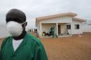 A man, wearing a protective mask, poses in front of an isolation center for people suffering from the Ebola virus, on August 12, 2014 at the airport in Abidjan, Ivory Coast