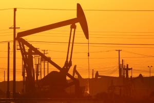 Pump jacks are seen at dawn in an oil field over the …