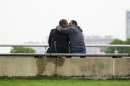 Two men kiss as they sit in a riverside park in New York