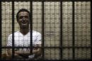 Egyptian activist Ahmed Douma stands behind bars during his trial at the New Cairo court, on the outskirts of Cairo