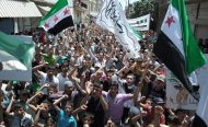 This citizen journalism image provided by Shaam News Network SNN, taken on Friday, July 6, 2012, purports to show protesters waving Syrian revolutionary flags and chanting slogans during a demonstration in Idlib, north Syria. Syria's military began large-scale exercises simulating defense against outside "aggression," the state-run news agency said Sunday an apparent warning to other countries not to intervene in the country's crisis. (AP Photo/Shaam News Network, SNN)THE ASSOCIATED PRESS IS UNABLE TO INDEPENDENTLY VERIFY THE AUTHENTICITY, CONTENT, LOCATION OR DATE OF THIS HANDOUT PHOTO