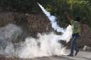 Palestinian protester returns a tear gas canister fired by Israeli troops during clashes following the funeral of Palestinian youth Laith al-Khaldi, in Jalazoun refugee camp near the West Bank city of Ramallah