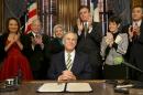 Texas Gov. Greg Abbott, surrounded by lawmakers, signs a proclamation making today, February 2, 2015, "Chris Kyle Day" in Austin, Texas. Two years after Kyle's death, and days before the man accused of killing him goes to trial, the retired SEAL was honored by his home state. (AP Photo/Austin American-Statesman, Ralph Barrera)