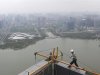 A worker walks on the roof of an office building construction site near a lake in Hefei