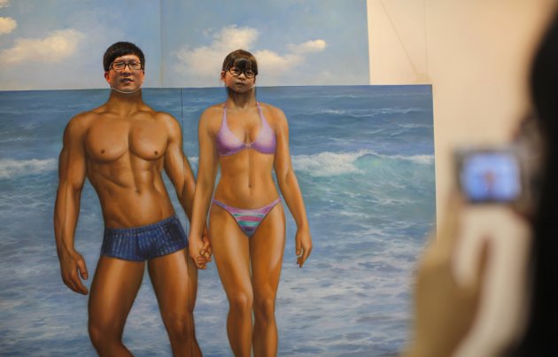 Man and his daughter pose for a photograph behind a 3D painting at the 2012 Magic Art Special Exhibition in Hangzhou
