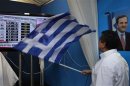 Conservative New Democracy supporter waves Greek flag by television screen showing exit polls in main New Democracy campaign center in Athens' Syntagma square
