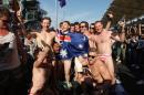 In this Sunday, Oct. 2, 2016 photo, Australian men pose for a photo in Budgy Smuggler-brand swimsuits decorated with the Malaysian flag at the conclusion of the Malaysian Formula One Grand Prix in Sepang, Malaysia. Malaysian authorities who have detained nine Australians for three nights would regard their actions in stripping down to their briefs and drinking beer from shoes as premeditated, Australia's foreign minister said Wednesday. (AP Photo)