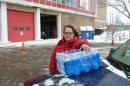 In a photo from Jan. 2, 2016, Rabecka Cordell picks up a case of bottled water outside the fire station in Flint, Mich. 