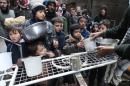 Residents of Syria's Yarmuk Palestinian refugee camp, south of Damascus, gather to collect aid food at the adjacent Jazira neighborhood on February 13, 2015