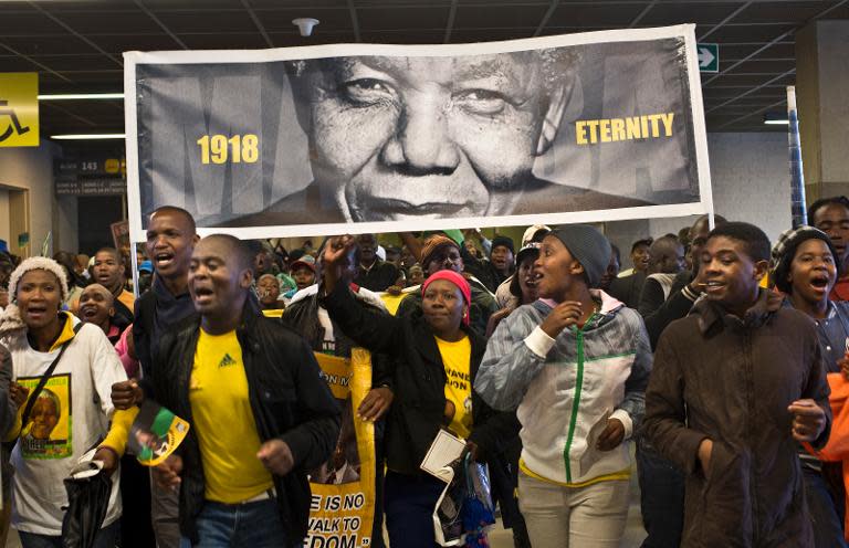 People holding a giant portrait of Nelson Mandela arrive moments before the memorial service on December 10, 2013 at Soccer City Stadium in Johannesburg