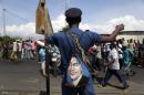 A police officer with a bag depicted the image of US President Barack Obama, stands on patrol as protesters march through the Musaga district of Bujumbura, in Burundi, Monday, May 11, 2015. Police and army negotiated with over 2000 protesters to allow delivery trucks to enter the city. One person was killed in a clash with Burundi's police on Sunday in demonstrations in the capital, Bujumbura, as the government ordered a ban on any further street protests over President Pierre Nkurunziza's bid for a third term in power. (AP Photo/Jerome Delay)