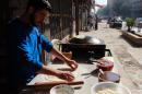 A Syrian man prepares bread on a typical domed metal griddle, in the northern city of Aleppo on November 3, 2013