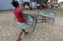 A woman and a boy carry a bed frame at a shelter for people affected by the earthquake in Managua