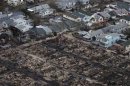 People stand amidst burnt houses, near those which survived in Breezy Point of Queens, after it was devastated by Hurricane Sandy