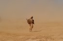 A British soldier walks near the Pimon military camp in Nad-e Ali district of Helmand province on March 25, 2010