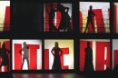 Silhouettes of models behind screens that display the name of French fashion designer Jean-Paul Gaultier as part of his Ready to Wear Fall-Winter 2013-2014 fashion collection, presented, Saturday, March 2, 2013 in Paris. (AP Photo/Jacques Brinon)