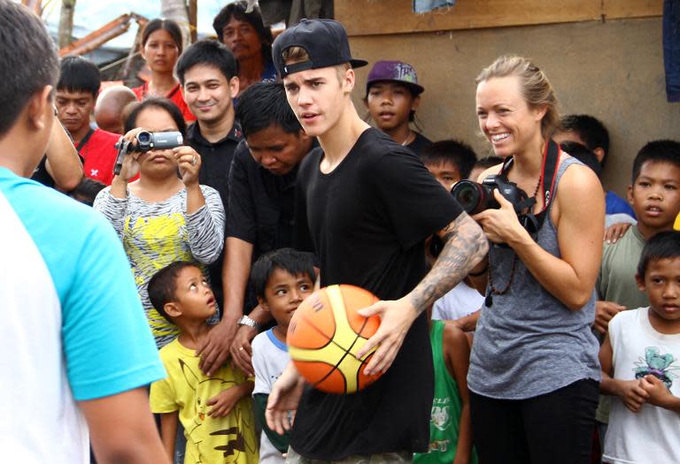 Justin Bieber (centre) plays basketball with a young survivor of Super Typhoon Haiyan in Palo, Leyte province on December 10, 2013