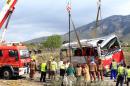 Emergency personnel look on as a crane rights a bus on the AP-7 motorway near Freginals, south of Tarragona, northeast Spain, after a fatal accident early on March 20, 2016