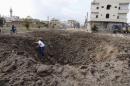 A man walks out of a crater caused by what activists said was a barrel bomb dropped by forces loyal to Syria's President Bashar Al-Assad in the town of Dael, north of Deraa