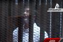 In this image taken from Egyptian state TV, toppled President Mohammed Morsi stands inside a glass-encased metal cage in a courtroom in Cairo, Tuesday, Jan. 28. 2014. Morsi was separated from other defendants for the start of a new trial Tuesday over charges from prison breaks during the country's 2011 revolution. (AP Photo/Egyptian State TV)