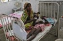 Sick boy lies on his mother's lap inside hospital after he consumed contaminated meals given to children at a school on Tuesday, in the eastern Indian city of Patna