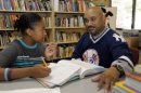 In this Aug. 7, 2012 photo, Phillip Covington, right, talks with his son Giovanni as he works on a mathematics lesson in the library of Todd Academy in Indianapolis. Struggling Indiana public school districts are buying billboard space, airing radio ads and even sending principals door-to-door in an unusual marketing campaign aimed at persuading parents not to move their children to private schools as the nation's largest voucher program doubles in size. (AP Photo/Michael Conroy)