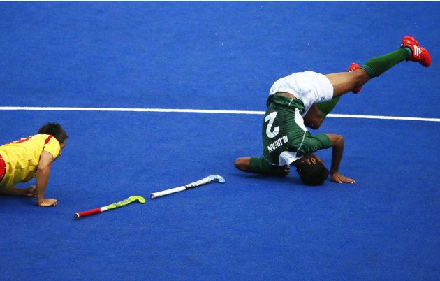 Spain's Pablo Amat and Pakistan's Muhammad Irfan fall during their men's Group A hockey match at the London 2012 Olympic Games