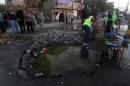 Iraqis gather around a crater left behind following a car bomb that targeted a tent set up to host Shiite pilgrims, leaving left six people dead and wounded 19, in the majority Shiite Sadr City district of northeast Baghdad, on November 3, 2014