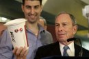 FILE - In this March 12, 2013 file photo, New York City Mayor Michael Bloomberg looks at a 64-ounce cup, as Lucky's Cafe owner Greg Anagnostopoulos, left, stands behind him, during a news conference at the cafe in New York. The mayors of New York, Los Angeles, Chicago and 15 other cities are reviving a push against letting government food vouchers be used to buy soda and other sugary drinks. In a letter to congressional leaders Tuesday, the mayors say it's 