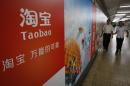 People walk past an advertising billboard showing the mobile app of Alibaba's Taobao consumer-to-consumer site at a subway station in Beijing Thursday, Sept. 18, 2014. Alibaba Group's U.S. stock offering is a wakeup call about an emerging wave of technology giants in China's state-dominated economy. (AP Photo/Vincent Thian)