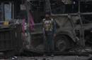 An Afghan policeman stands guard in front of a destroyed bus after the blast in Kabul