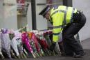 A police officer arranges floral tributes left by members of the public for victims of Monday's refuse truck accident in Glasgow, on December 23, 2014