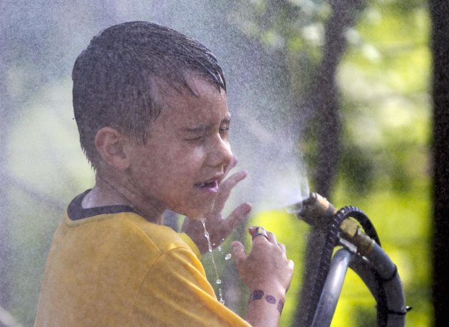 FILE - This July 6, 2012 file photo shows six-year-old Alexander Merrill of Sioux Falls, S.D., cooling off in a cloud of mist at the Henry Doorly Zoo in Omaha, Neb., as temperatures reached triple digits. Federal meteorologists say America was deep fried in 2012, becoming the hottest year on record by far. The National Climatic Data Center in Ashville, N.C., calculates that the average U.S. temperature in 2012 was 55.32 degrees Fahrenheit. That's a full degree warmer than the previous record of 1998. Normally, records are broken by about a tenth of a degree. (AP Photo/Nati Harnik, File)