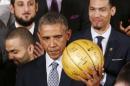 U.S. President Barack Obama holds up an autographed basketball as he welcomes the 2014 NBA Champion San Antonio Spurs to the East Room of the White House in Washington