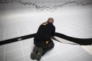 A worker puts finishing touches to a stage next to a graph at the Madrid stock exchange