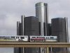 Two cars of the public rail are seen covered with a advertisement for 2014 Chevy Silverado pickup truck as they move past General Motors World Headquarters in Detroit
