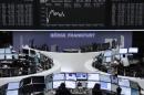 Traders are pictured at their desks in front of the DAX board at the Frankfurt stock exchange