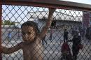 FILE - In this photo taken on Saturday, June 25, 2016 a child stands behind a fence during a protest against the living conditions at the Oreokastro camp, near the northern town of Thessaloniki, Greece. A government official in Athens on Wednesday, Aug. 3, 2106 said to the Associated Press that there is no sign yet that a deal between the European Union and Turkey to stop migrants coming to Europe has faltered since the attempted military coup in the country. (AP Photo/Giannis Papanikos, File)