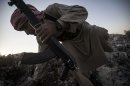 In this Sunday, Sept. 29, 2013 photo, a Syrian opposition fighter takes cover during exchange of fire with government forces in Telata village, a frontline located at the top of a mountain in the Idlib province, northwest countryside of Syria. (AP Photo)