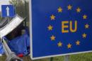 An EU sign is seen as a migrant rests at the border crossing from Slovenia in Trnovec