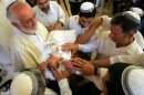 Members of the high priesthood place their hands to bless a baby after a Rabbi performed a ceremonial circumcision