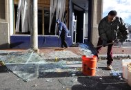 Robert Spano, left, and Alan Hugley clean up broken glass, Saturday, Nov. 24, 2012, outside of Punta cana Restaurant & Bar, a few blocks from the site of a Friday-evening gas explosion that leveled a strip club in Springfield, Mass. (AP Photo/Jessica Hill)