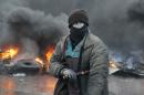 A protester stands at a burning barricades between police and protesters in central Kiev, Ukraine, Thursday Jan. 23, 2014. Thick black smoke from burning tires engulfed parts of downtown Kiev as an ultimatum issued by the opposition to the president to call early election or face street rage was set to expire with no sign of a compromise on Thursday. (AP Photo/Efrem Lukatsky)