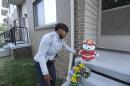 Beatrice Spears leaves a stuffed animal on the front porch of a home where an 8-year-old boy was shot and killed by a bullet fired from outside that pierced the wall of his home, hitting the child in bed, early Wednesday, July 30, 2014. (AP Photo/Detroit News, David Coates)