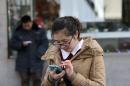 Chinese people check on their smartphones on a street in Beijing Monday, Feb. 16, 2015. On the Internet, in college classrooms and in corporate offices, the Chinese Communist Party has raised the virtual wall separating the world's most populous country from the rest of the globe. Experts say it reflects a distrust of outside influences that party thinks could threaten its control on society. (AP Photo/Andy Wong)