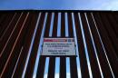 A Donald Trump for President campaign sticker is shown attached to a U.S. Customs sign hanging on the border fence between Mexico and the United States near Calexico, California