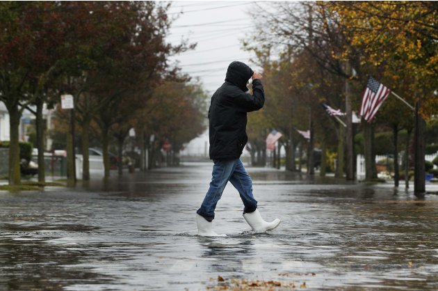 A man walks across a flooded street in the Belle Harbor section of the Queens borough of New York
