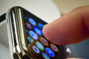 FILE - In this April 10, 2015 file photo, a customer examines Apple's new watch in New York. The first batch of Apple Watches will arrive in people's homes and offices Friday April 24, 2015. (AP Photo/Bebeto Matthews)